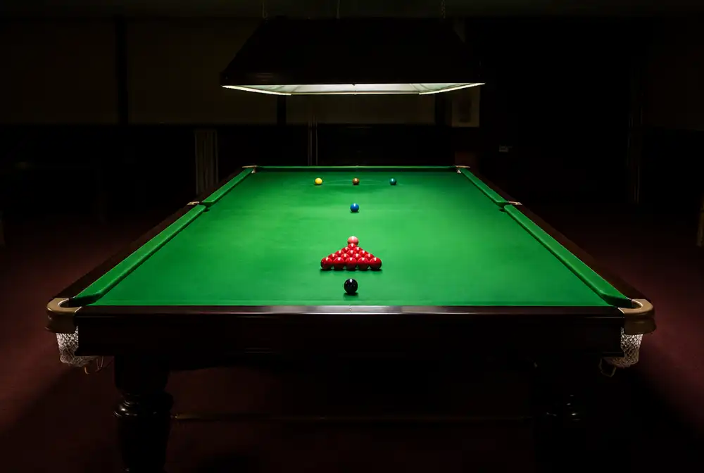 Snookertafel met de rode ballen in een driehoek onder een lamp